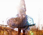 Blurry Portrait of Woman Standing in Grass Twirling Skirt