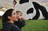 Mother and child watching giant hot-air balloons at the fair, St-Jean sur Richelieu, Quebec