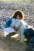 Mature woman playing with a dog on a beach, Toronto, Ontario