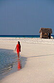 Republic of the Maldives, Lhaviyani Atoll,  Kanuhura Hotel, Woman walking by the sea