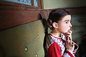 Portrait of a young girl sitting on a green bench seat