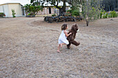 Young girl runing with her giant teddy bear in the garden