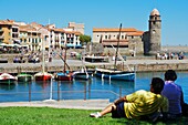 France, Lanquedoc Roussillon, Collioure, The marina port, couple resting on the lawn