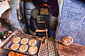 Kingdom of Morocco, Fes, Fes el Bali, Medina of Fes, Baker cooking flatbreads in front of his oven