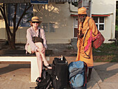 Female tourist waiting at train station and being watched by a sadhu at kanchipuram station, kanchipuram tamil nadu south india