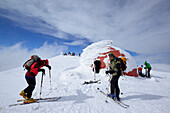 Group of persons back-country skiing standing on the summit of Monte Amaro with snow-covered bivouac, Monte Amaro, Majella, Abruzzi, Apennines, l' Aquila, Italy