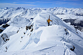 Female backcountry skier ascending to Vallatscha, Sesvenna range and Grison Alps with Swiss National Park in background, Ofenpass, Grisons, Switzerland