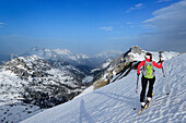 Female backcountry skier ascending to Diesbacheck, Leoganger Steinberge in background, Berchtesgaden Alps, Berchtesgaden National Park, Upper Bavaria, Bavaria, Germany