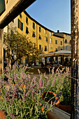 Blick in einen Spiegel zeigt Häuser und Restaurant an der ovalen Piazza dell'Anfitheatro, Lucca, Toskana, Italien