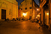 People in the old town in the evening and a bar with outdoor tables in the evening, Lucca, Tuscany, Italy