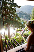 Woman enjoying view from a balcony of a hotel, Deia, Majorca, Spain