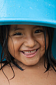 Ein junges Mädchen mit hellblauen Eimer auf dem Kopf im Dorf Agua Blanca in der Nähe des Machalilla Nationalparks, nahe Manta, Manabi, Ecuador, Südamerika