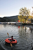 Boy in a paddle boat near the boat hire and cafe in Schliersee, Schliersee lake, Bavaria, Germany