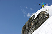 Freerider springt im Tiefschnee über Felsklippe, Disentis, Surselva, Graubünden, Schweiz