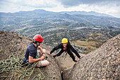 Woman climbing at Cathedral Rock, man belaying her, Mount Buffalo, Australian Alps, Victoria, Australia