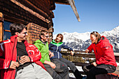 Four persons sitting on terasse of an alpine restaurant, Alp Fops, Lenzerheide, Canton of Graubuenden, Switzerland