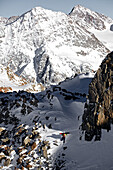 Junger Snowboarder läuft auf den Gipfel eines Berges, Pitztal, Tirol, Österreich