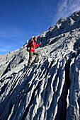 Woman ascending on limestone slab to Hoher Goell, Berchtesgaden National Park, Berchtesgaden Alps, Upper Bavaria, Bavaria, Germany