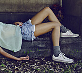 Young Woman Laying Across Stone Bench
