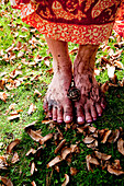Woman's Muddy Bare Feet Standing on Grass and Leaves