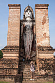 Tourists Contemplating A Standing Buddha In The Historical Park Of Sukhothai, Old City Listed As A World Heritage Site By Unesco, Thailand, Asia