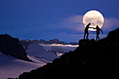 Composite: Hikers Silouetted On A Ridge Above The Juneau Ice Field With The Full Moon In The Background, Southeast Alaska