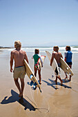 South Africa, Surfers walking beach carrying boards, Mossel Bay