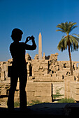 Silhouette of woman photographing ruins of Karnak Temple, Precinct of Amun, Luxor, Egypt