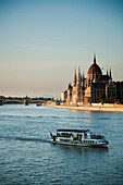 Tourist boats passing along Danube river, past Hungarian Parliament Building, Budapest, Hungary