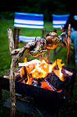 Spit roast chicken over open fire at Llyn Gwynant Campsite, Nant Ggwynant, Snowdonia National Park, North Wales, Wales, UK