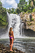 Young girl in bikini next to Tegenungan Waterfall, Ubud, Bali, Indonesia