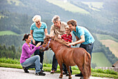 Multi generational family petting a pony, Styria, Austria