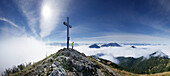 Hiker beside a summit cross, Heimgarten, Bavaria, Germany