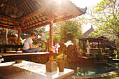 Woman sitting in a pavilion while reading, Ubud, Bali, Indonesia