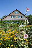 Old wooden farmhouse with wild flowers in the garden, Lindau, Lake Constance, Swabia, Bavaria, Germany, Europe