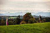 Paar in Tracht steht auf einer Wiese vor Alpenpanorama, Bad Tölz, Oberbayern, Bayern, Deutschland