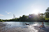 Frau spielt mit einem Hund auf einer Kiesbank an der Isar, Wittelsbacherbrücke, München, Bayern, Deutschland