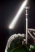 Ship's searchlight probes darkness for icebergs, South Georgia Island, Antarctica