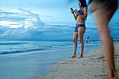 Chinesische Touristinnen am Abend am Strand, Bewegungsunschärfe, Kuta, Bali, Kleine Sundainseln, Indonesien