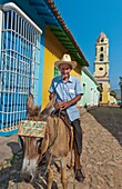 Trinidad Cuba old man on donkey selling rides and photos in old colonial town with cobble stones and church