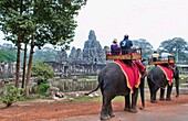 Famous Bayon Temple with touists riding elephants in Siem Reap Cambodia Asia