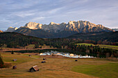 Mountain pasture with hay barns, view over Geroldsee lake to the Karwendel mountains, near Mittenwald, Bavaria, Germany
