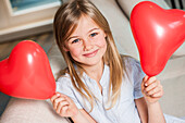 Girl holding two heart-shaped balloons, Hamburg, Germany