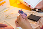 Hebamme nimmt Abdruck von einem Fuß eines Neugeborenen, Leipzig, Sachsen, Deutschland