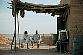 Two men in front of their hut in Wadi Halfa, River Nile in the background, Sudan, Africa