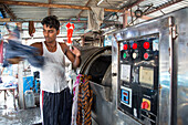 Man washing clothes at Mahalaxmi Dhobi Ghat open air laundromat, Mumbai, Maharashtra, India