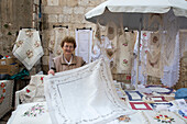 Woman presenting handicraft lace products for sale at a market stand in the old town, Dubrovnik, Dubrovnik-Neretva, Croatia