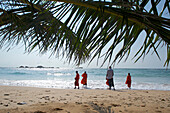 View through palm leaves towards the beach, buddhist novices at the sea, Hikkaduwa, Southwest coast, Sri Lanka