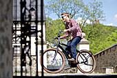 Young man riding an electric bicycle in a city, Tanna, Thuringia, Germany