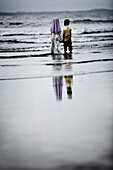 Two children standing in water at beach, Jakarta, Java, Indonesia